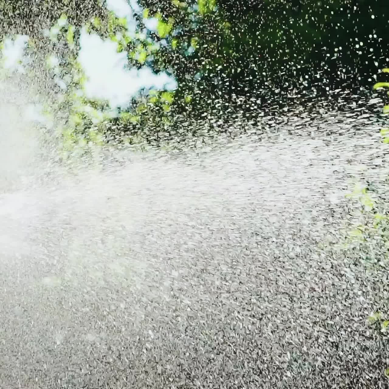 Plastic automatic water sprinkler with strong spray watering grass in garden. Slow Motion.