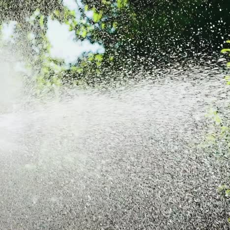 plastic automatic water sprinkler with strong spray watering grass in garden. slow motion.