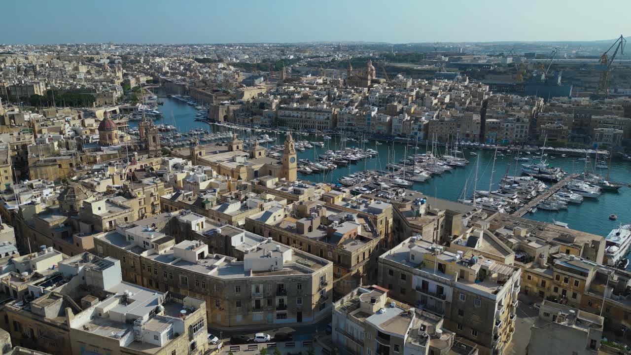 Vista aérea de Birgu, Malta, mostrando as ruas históricas, fortificações e a antiga área portuária. Edifícios tradicionais de calcário e o porto mediterrâneo capturados de cima
