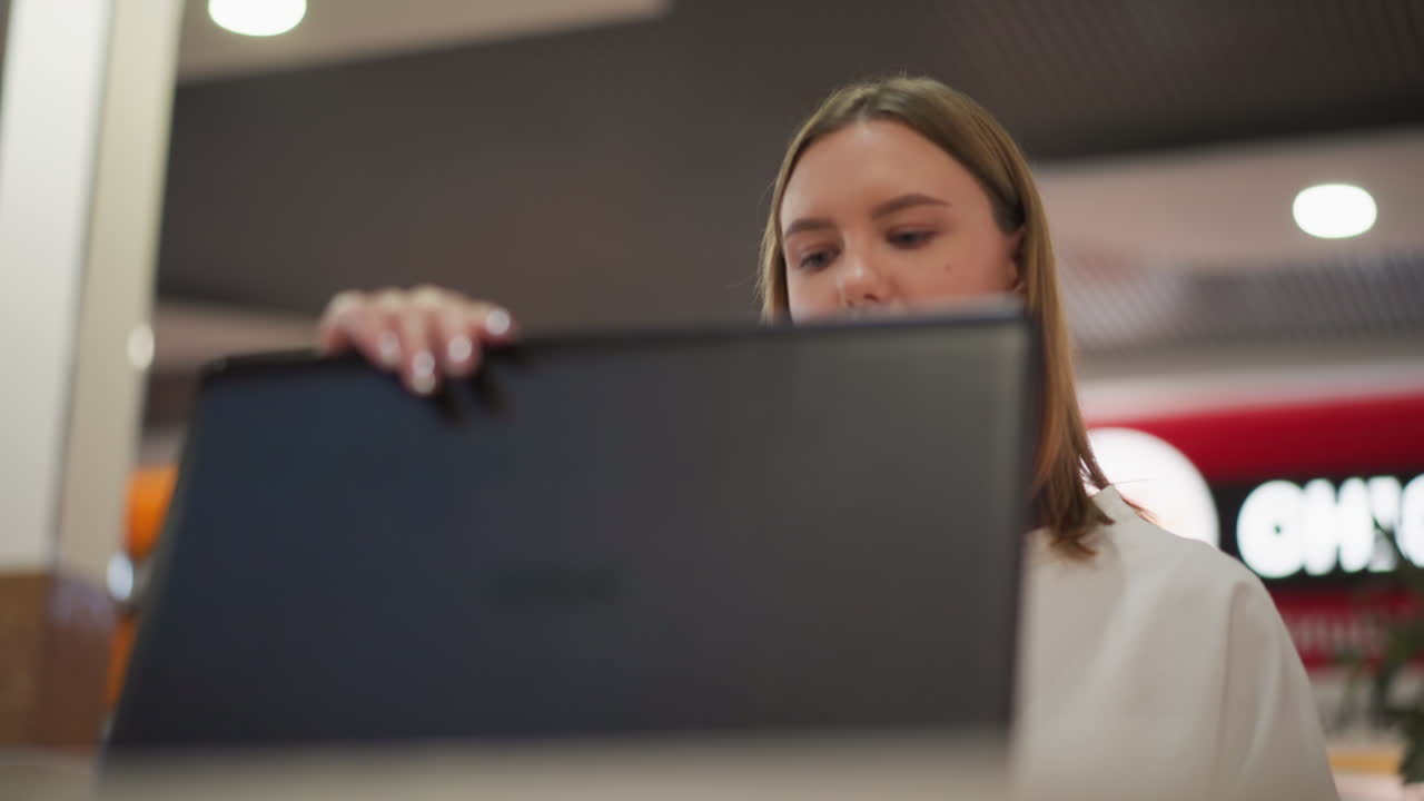 primer plano de una computadora portátil abierta por una persona en un entorno de centro comercial moderno, con luces de fondo borrosas vibrantes y atmósfera urbana