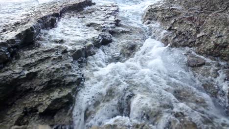 Waves-crashing-into-rocks-near-Budva-old-town-on-the-coastline-of-Montenegro-on-the-Adriatic-coastline-on-a-sunny-sunset-afternoon