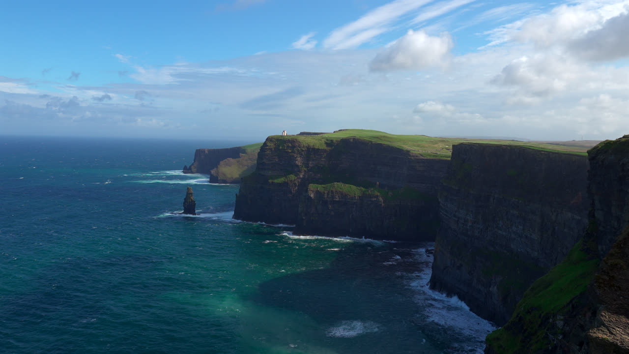 The Cliffs of Moher rise majestically from the ocean, their towering rock faces shaped by time. The vast coastline and crashing waves create a truly dramatic Irish landscape.