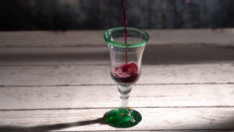 clip de vino tinto en bucle sin costuras que se vierte en un vaso rústico con fondo azul