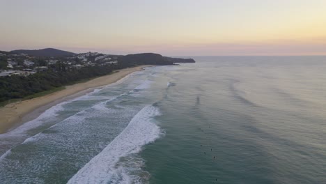 Olas-Espumosas-Salpicando-La-Orilla-Arenosa-De-La-Playa-Del-Sol-Al-Atardecer-En-Queensland,-Australia---Toma-Aérea