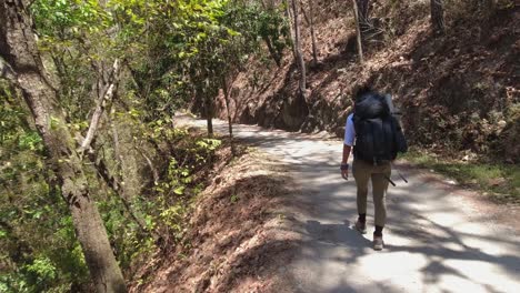 Walking-POV-follows-female-backpacker-on-road-on-jungle-mountainside