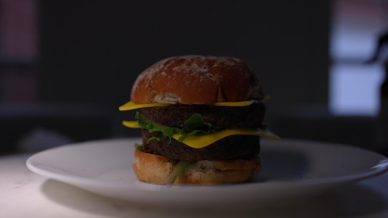 A double plant based cheeseburger under a moving spotlight
