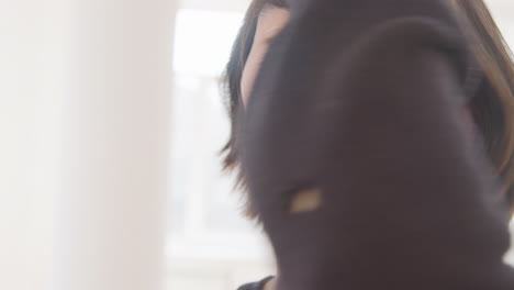 close up view of contemporary male japanese dancer who is training dance moves with her hands and face while looking at camera in the studio