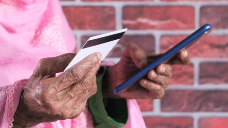 mujer anciana que utiliza teléfono móvil y tarjeta de crédito para el pago en línea