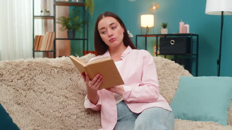 young woman reading book on sofa turning pages slowly reflecting deeply on story absorbing meaning