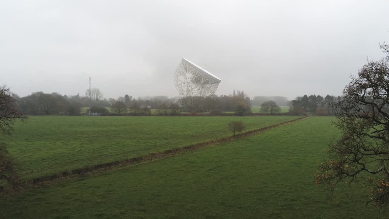 телескоп ловелл обсерватории джодрелл бэнк, возвышающийся над туманной сельской местностью