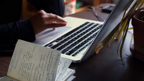 camera tracks back on a laptop keyboard as an asian woman types on the keyboard