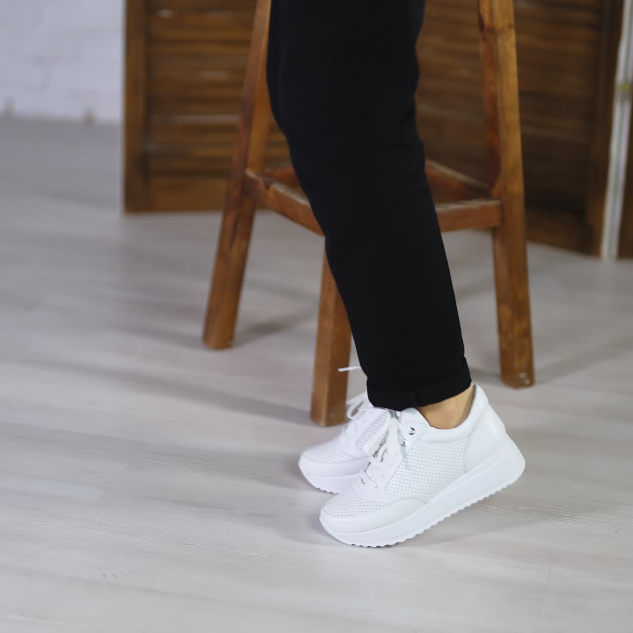 Woman wearing black trousers dances in white sneakers. New fashionable footwear demonstration concept