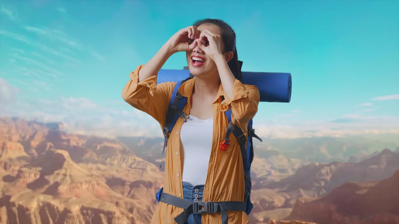 Asian Female Hiker With Mountaineering Backpack Smiling And Making Binoculars Gesture Then Looking Around While Traveling At The Top Of Mountain