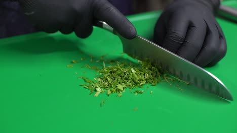 chef hands cutting parsley on green cutting board, close up