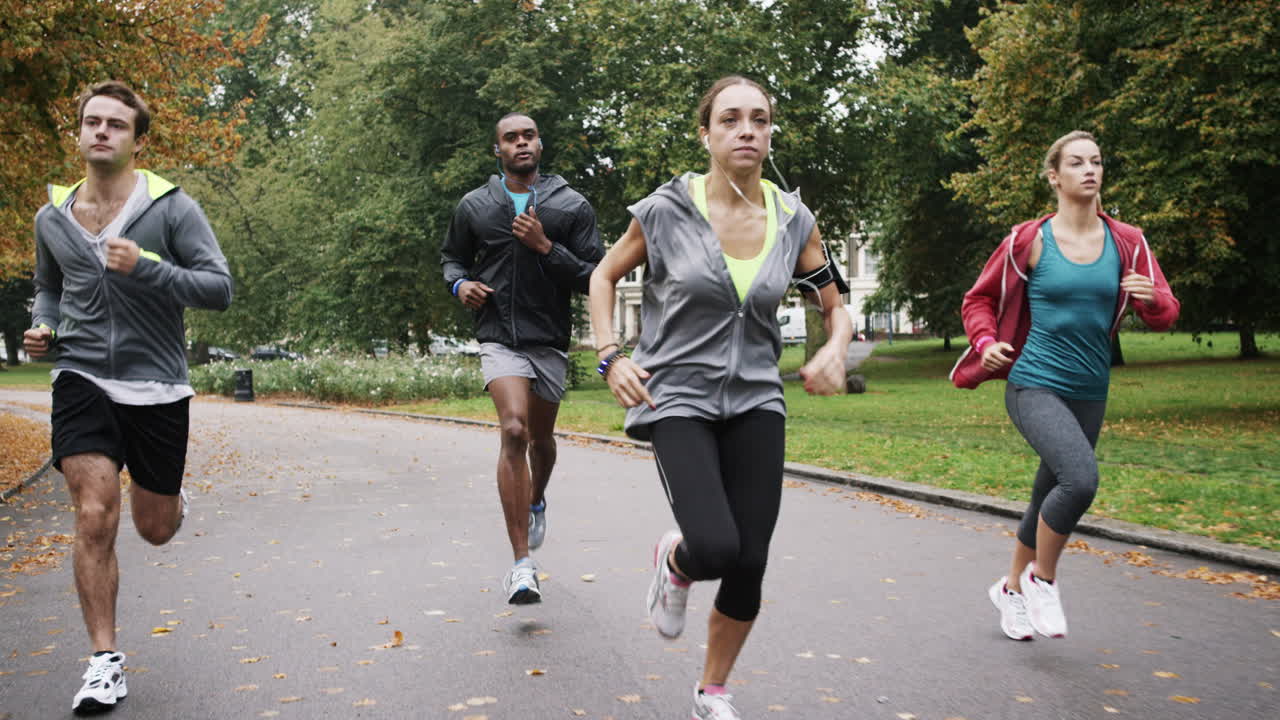 Group of runners running in park wearing wearable technology connected devices