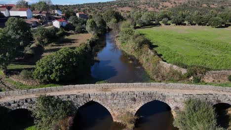 drone vuela sobre el puente romano al lado de una pequeña ciudad fluvial en portugal