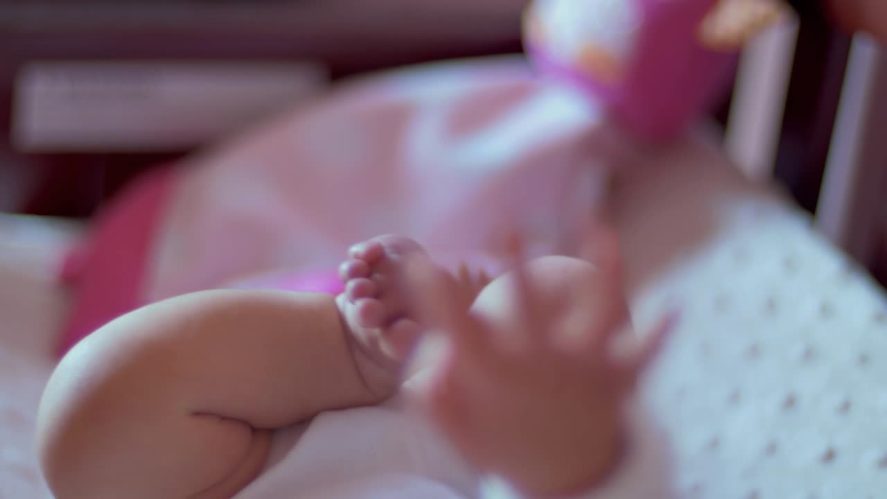 Primo piano dei piedini che si muovono di una neonata mentre è sdraiata nella sua culla