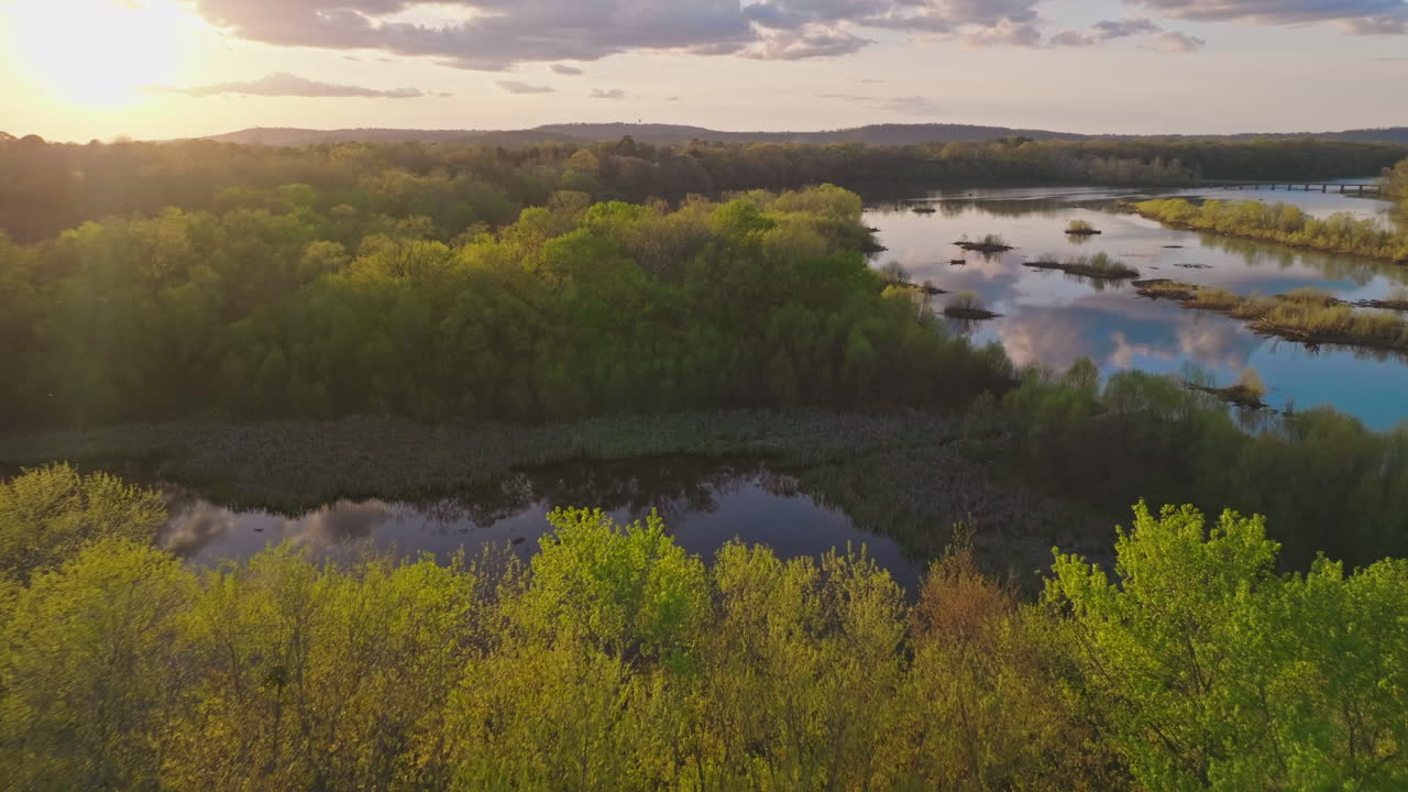 Dolly back reveals sunset over forest treetops at Lake Sequoyah, White River, near Fayetteville Arkansas - Aerial