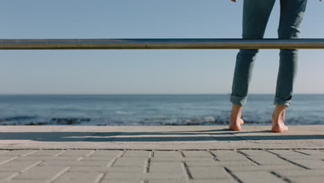 Piernas-De-Mujer-Caminando-Descalzas-En-El-Muelle-Junto-Al-Mar-Disfrutando-De-Unas-Relajantes-Vacaciones-De-Verano-Viendo-El-Hermoso-Océano