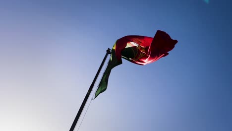 Zeitlupenansicht-Der-Flagge-Portugals,-Die-An-Einem-Sonnigen-Tag-Vor-Blauem-Himmel-Fliegt