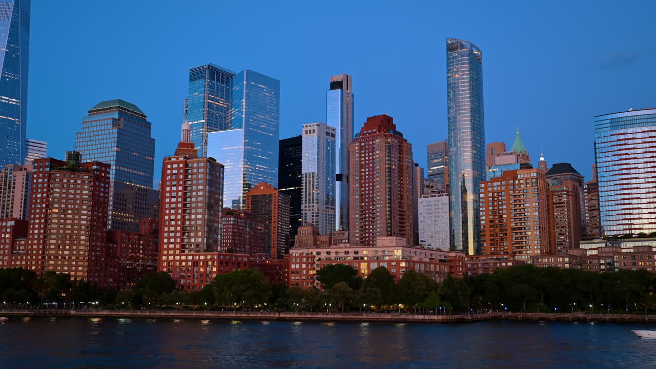 Arranha-céus residenciais de Battery Park City na hora azul. Arquitetura densa dos edifícios na orla de Manhattan com as luzes da cidade refletindo no Rio Hudson.