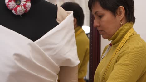 modista femenina trabaja en maniquí con vestido blanco