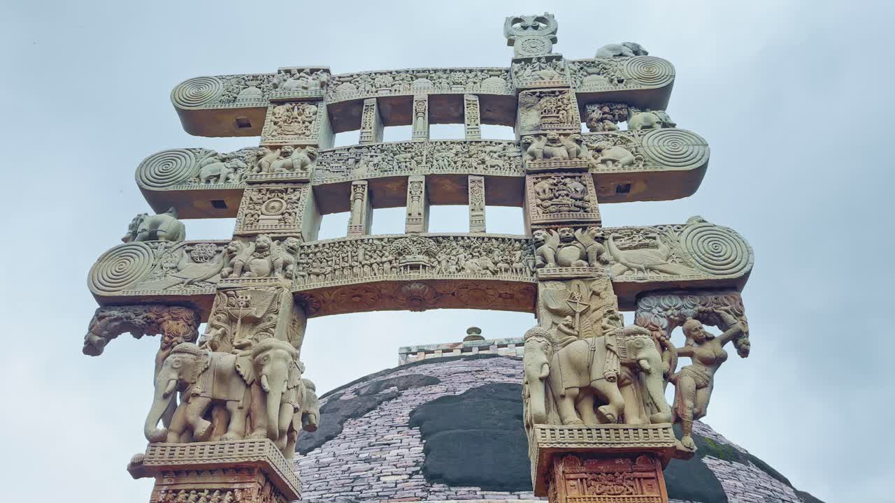 A tilt-up shot unveils the magnificent Sanchi Stupa crowned with its ornate torana. The intricate carvings and towering gateway highlight the grandeur of this UNESCO World Heritage site