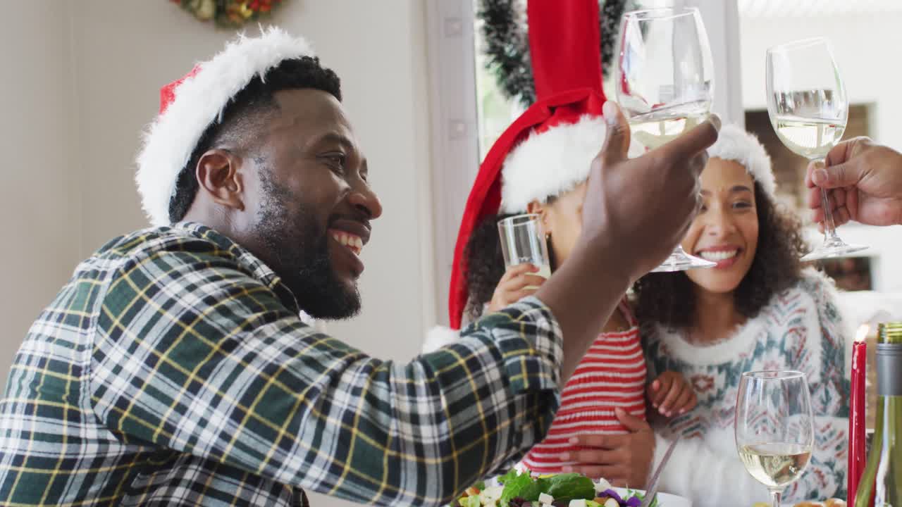 feliz familia afroamericana usando sombreros de santa y celebrando en la cocina