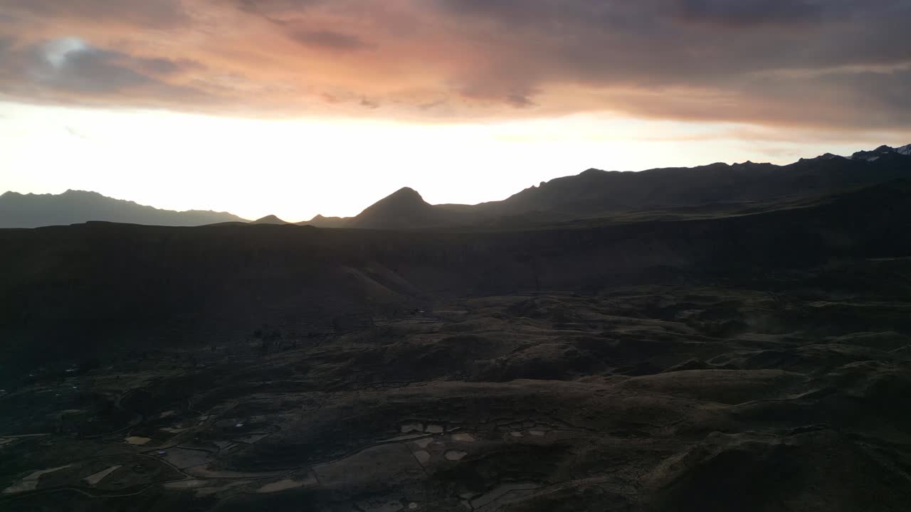 Drone reveal of soft dusk light bathing terraced farmlands in the Andes, golden highlights lingering before darkness takes hold