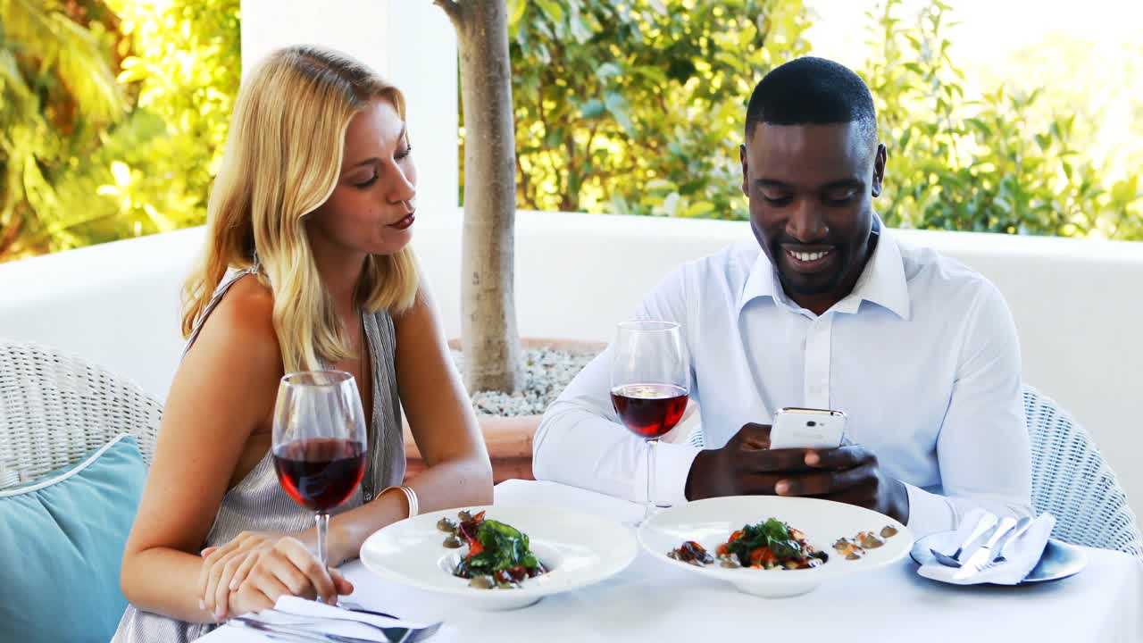 Man ignoring bored woman while using mobile phone