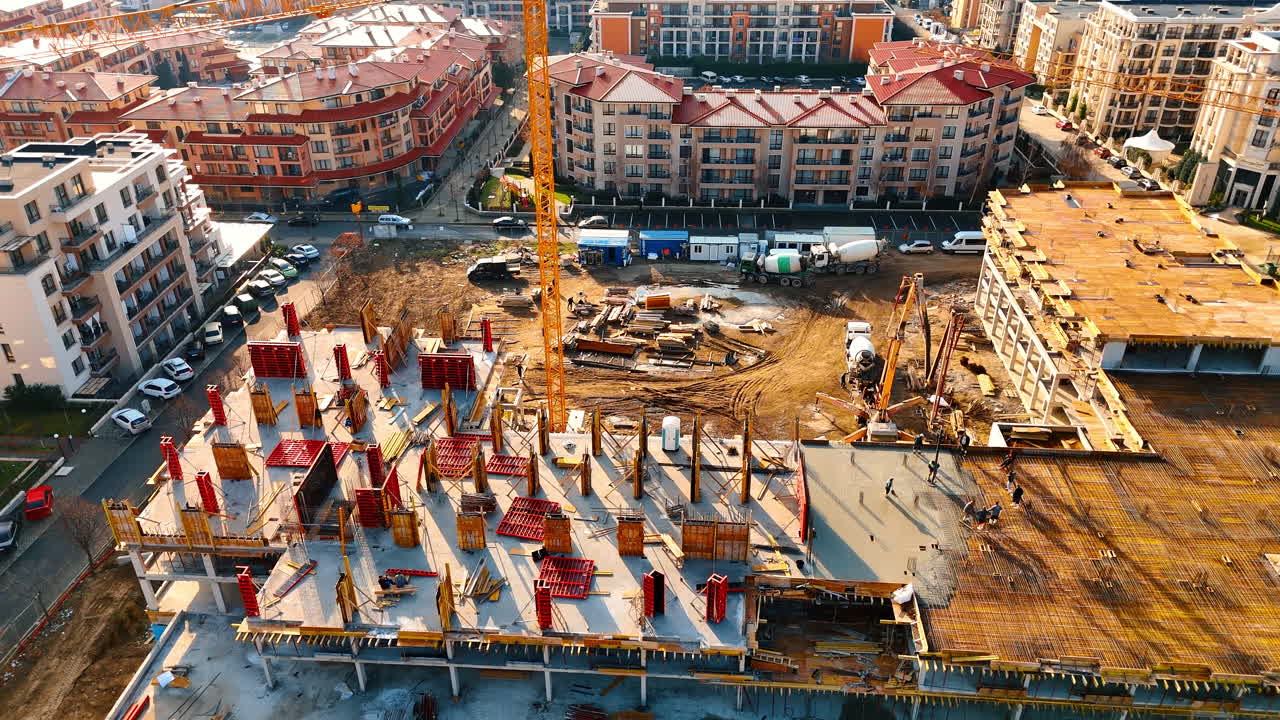 Urban construction site daytime. Workers operate machinery at a construction site with cranes and buildings in the background