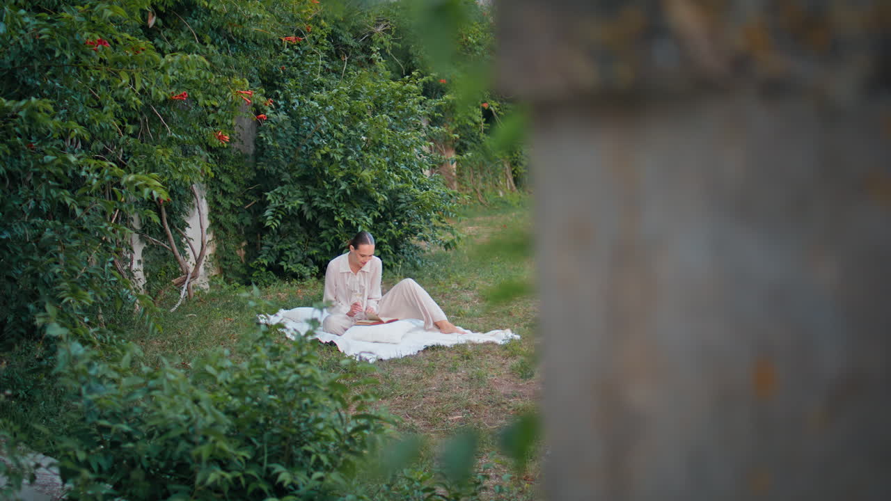 """녹색 정원에서 담요에서 만적 인 문학을 읽는 여자, 소녀는 소설을 즐긴다."""