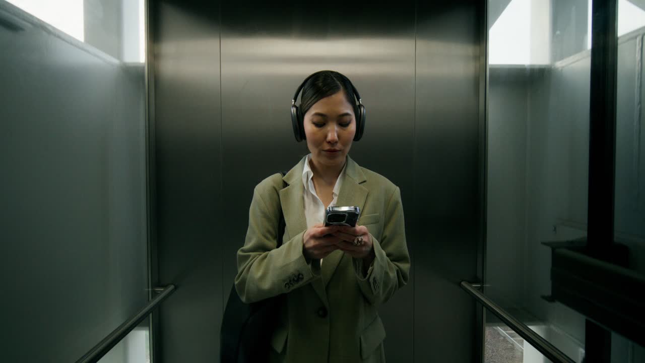 Businesswoman in Elevator Listening to Music