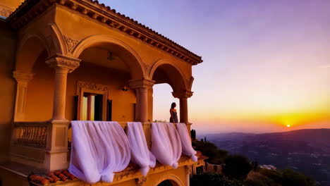 woman on a balcony overlooking a sunset mountain view