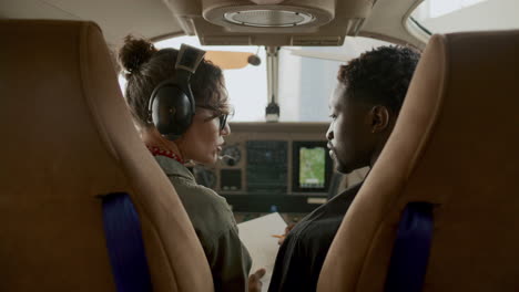 pilot and technician sitting in cockpit and discussing aircraft checklist