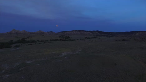 a slow cinematic drone shot panning towards the moon at dusk