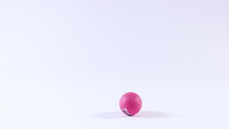 una pelota rosa rebota en una superficie blanca