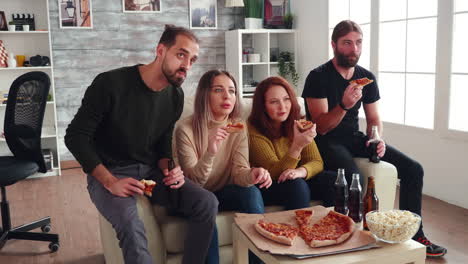 grupo de amigos sentados en el sofá comiendo pizza