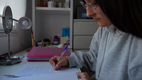 chica con gafas escribiendo notas en un cuaderno en la sala de estudio
