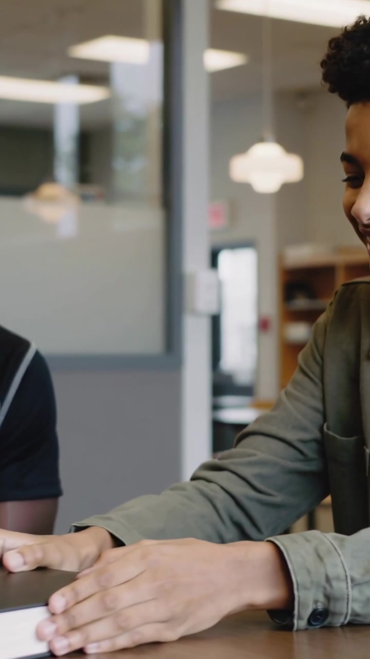 Vertical video: Reaching right peer placing hands on black book at study table, studying in jacket
