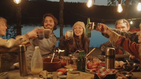 amigos tocando la guitarra y bebiendo en una cena de campamento