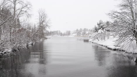 Drone-shot-of-a-beautiful-lake-in-Sweden-during-a-cold-winter-day-with-snowfall