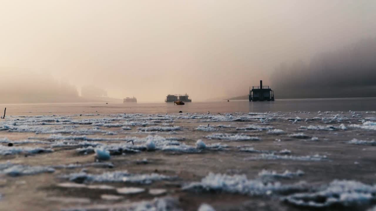 Winter icy lake with frozen houseboats in foggy morning.
