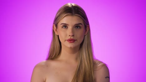 joven mujer caucásica alegre saca la lengua, mirando a la cámara, toma de estudio