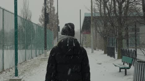 Frau-Im-Schwarzen-Mantel-Geht-Auf-Leerem-Schneeparkweg