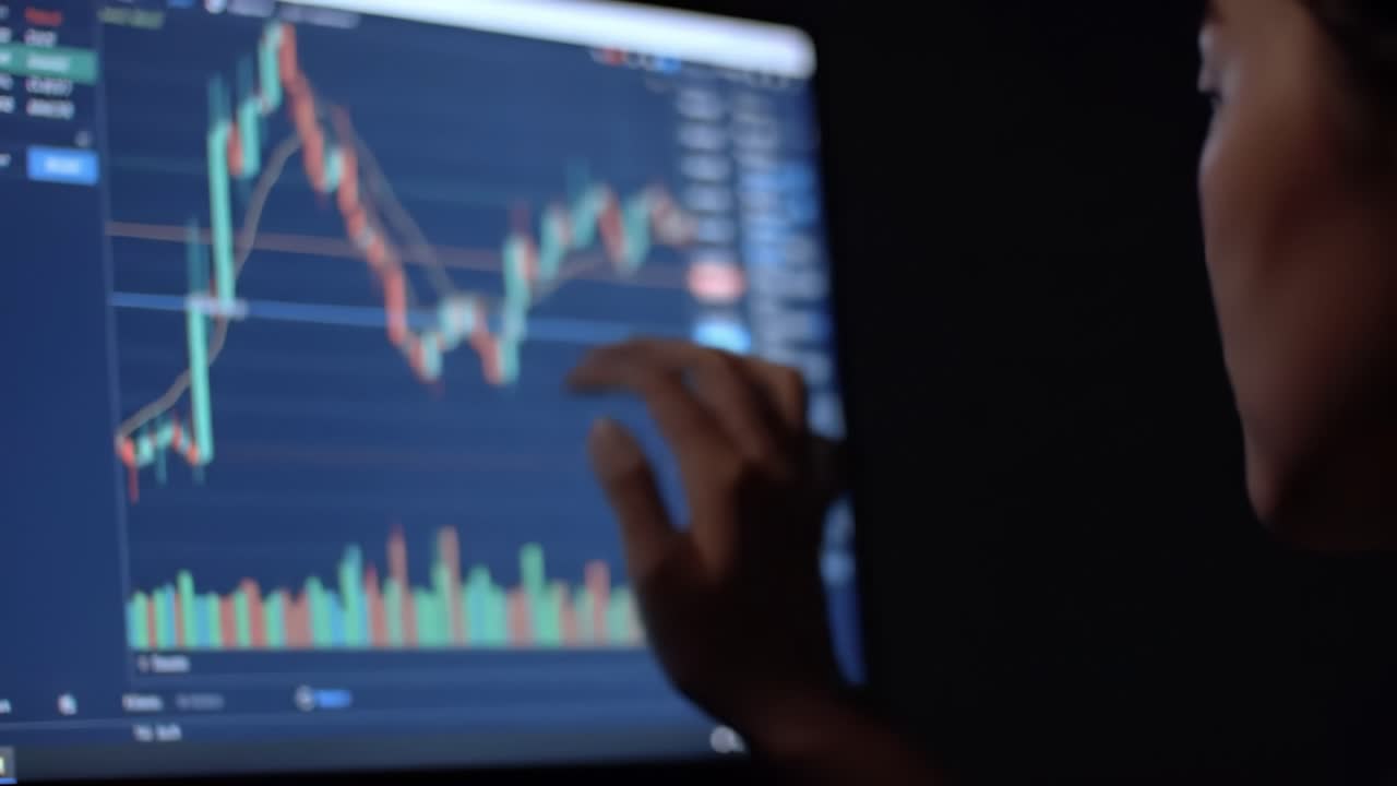 Trader analyzes market trends and stock performances in a professional trading studio during evening hours, focusing on real-time data and charts for informed decision-making.