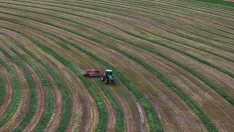 Henificar-Y-Rastrillar-Heno-En-Hileras-Ordenadas-En-Un-Día-Soleado:-Vista-Aérea-De-Campos-Circulares-En-La-Hermosa-Columbia-Británica-Con-Un-Tractor-Verde-En-El-Trabajo