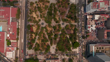 Aerial-birds-eye-overhead-top-down-panning-view-of-public-urban-park-Alameda-Central-and-surrounding-streets-with-traffic.-Mexico-City,-Mexico.