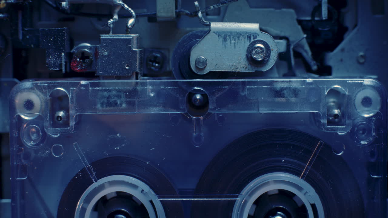 차가운 파란색 조명 아래 재생 헤드와 핀치 롤러가 있는 마이크로카세트 레코더 릴