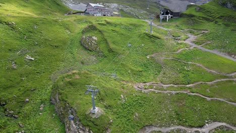 Drohne-Luftaufnahme-Einer-Großen-Wiese-Und-Einer-Seilbahnstruktur,-Um-Den-Berg-Hinaufzugehen,-Schweizer-Alpen,-Engelberg,-Obwalden